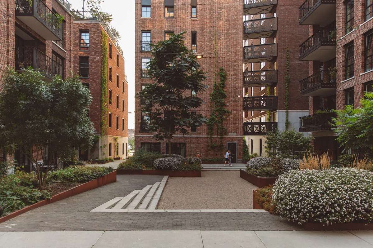 Binnenplaats met groene beplanting en rode bakstenen appartementen aan de Karl Weisbardstraat.